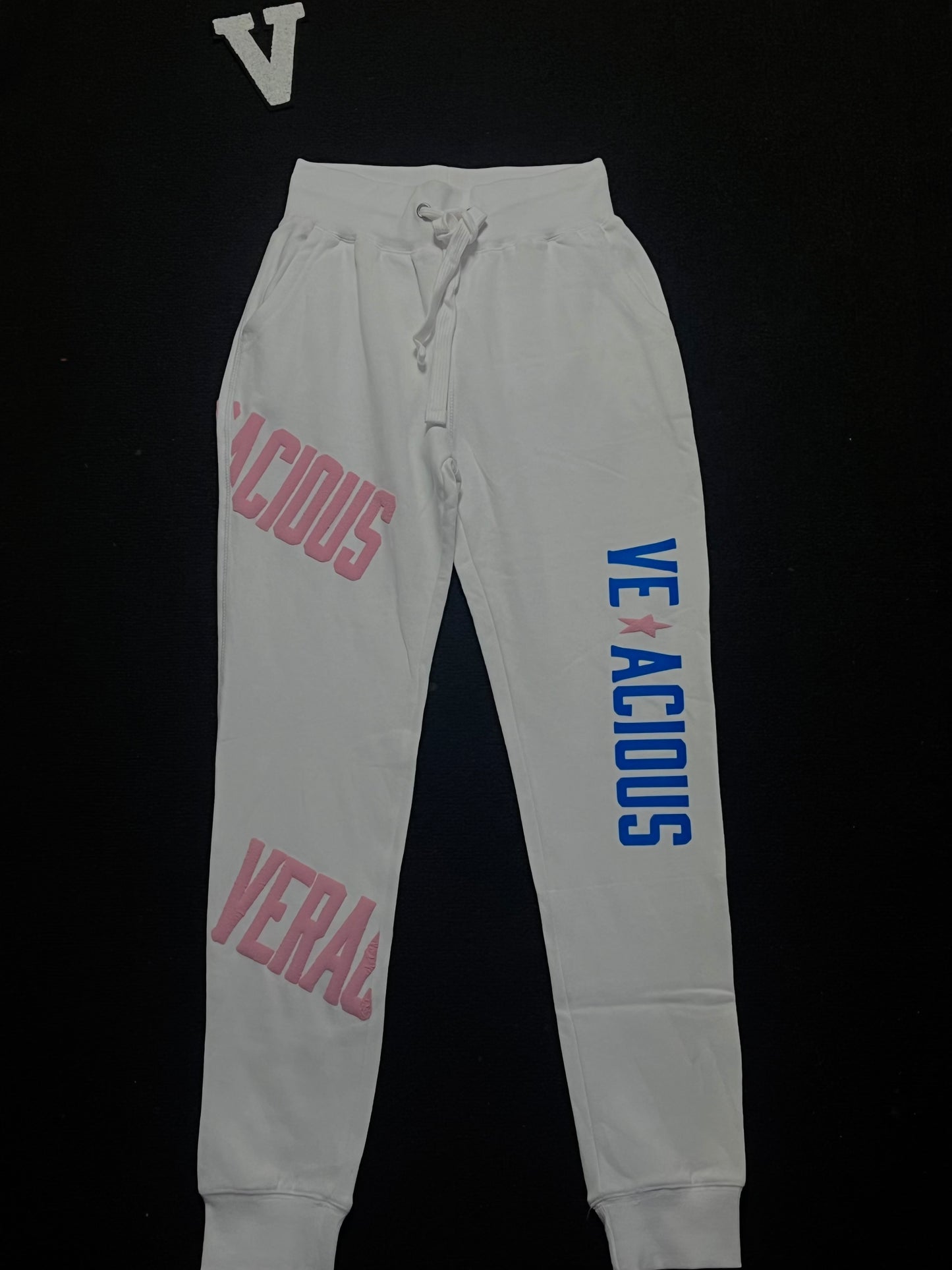 white sweatpants with pink and blue text on a black background