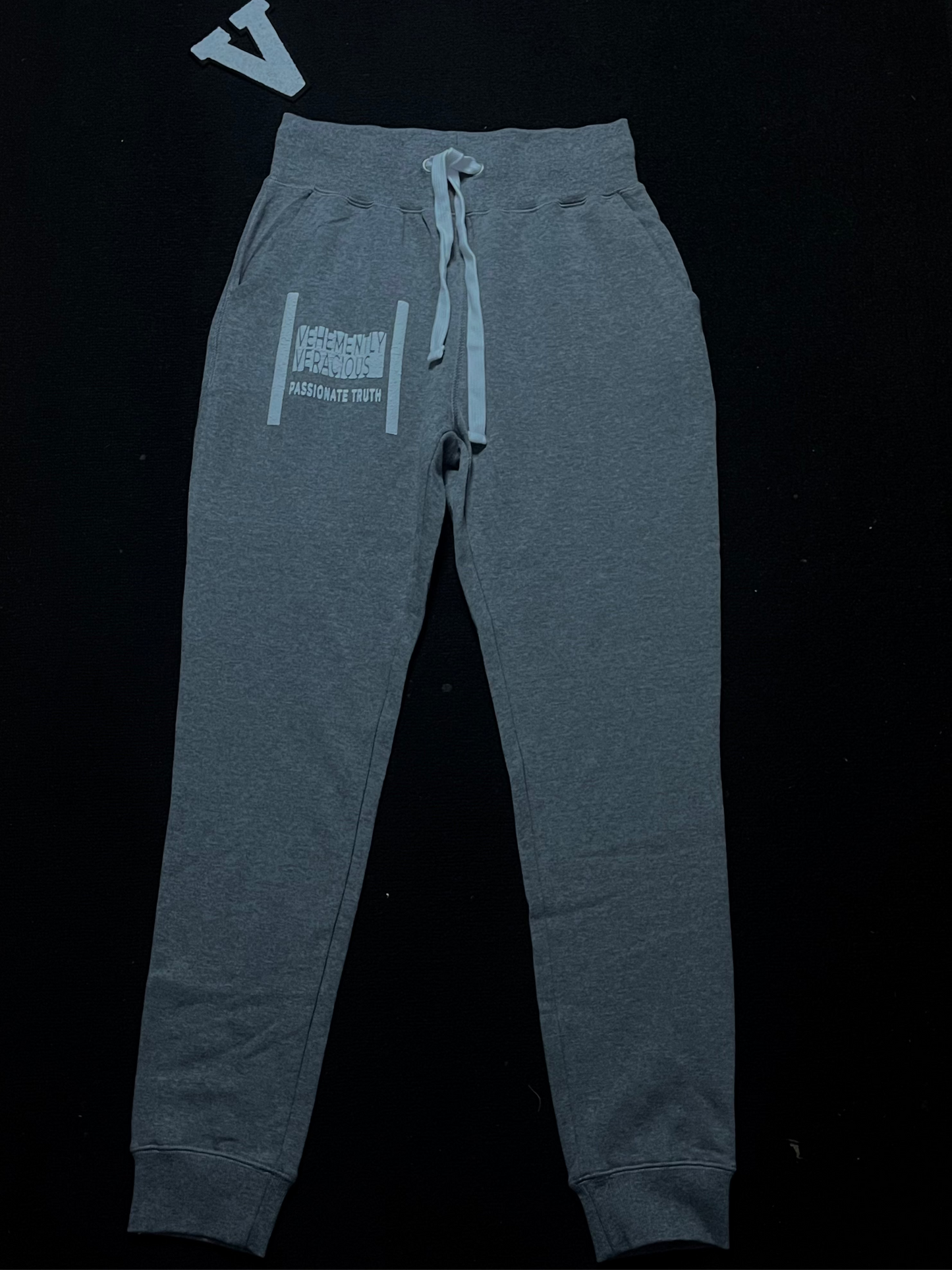 Gray sweatpants with a logo on the chest against a black background